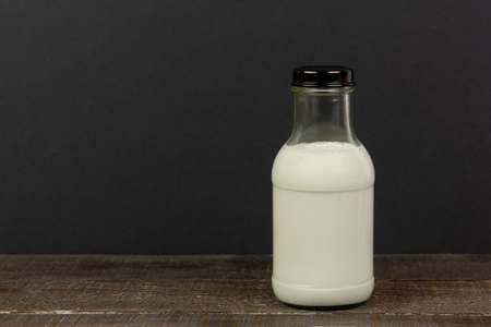 Milk in bottle on wooden table and black background.の写真素材