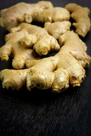 Fresh ginger on black wooden background. Ginger is a food and herb for healthcare.