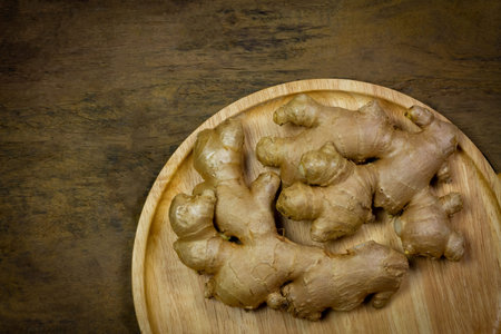 Fresh ginger on wooden plate on rustic wooden background. Ginger is a food and herb for healthcare.