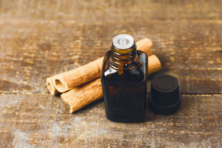 Essential cinnamon oil in bottle on rustic wooden background. Toned image.の写真素材