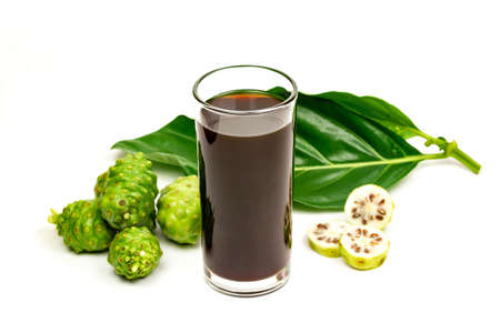 Noni juice in transparent glass cup and fresh noni fruit with green leaf isolated on white background.の写真素材