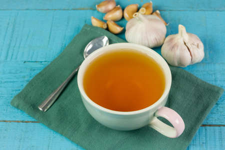 Garlic tea in ceramic cup with garlic on blue wooden background.の写真素材