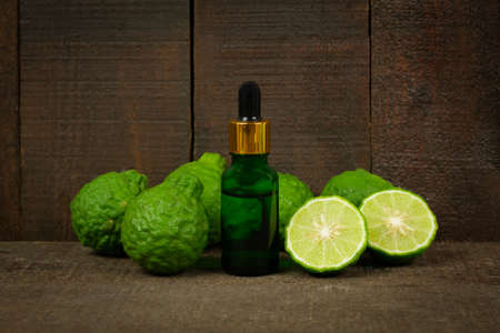 Bergamot oil in glass bottle and fresh bergamot fruit on rustic wooden background.の写真素材