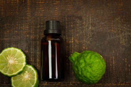 Bergamot oil in bottle and fresh bergamot fruit on rustic wooden background, top view.の写真素材