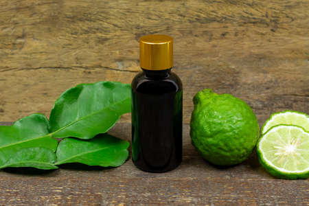 Bergamot oil in glass bottle and fresh bergamot fruit on rustic wooden background.の写真素材
