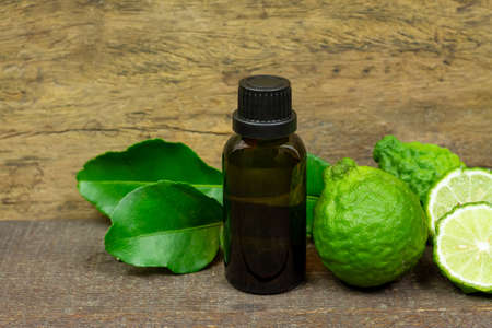 Bergamot oil in glass bottle and fresh bergamot fruit on rustic wooden background.の写真素材