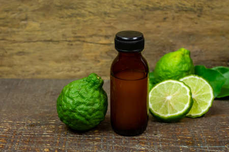 Bergamot oil in glass bottle and fresh bergamot fruit on rustic wooden background.の写真素材