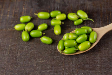 Fresh Neem fruit on wooden spoon on rustic wooden background.の写真素材