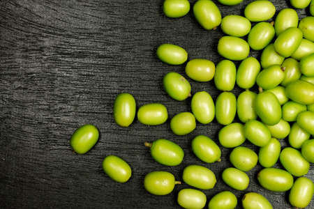 Fresh Neem fruit on black wooden background. Neem fruit is an excellent moisturizing and contains various compounds that have insecticidal and medicinal properties.の写真素材