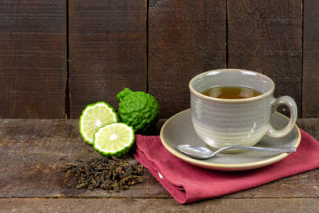 Bergamot tea or Earl Grey tea in ceramic cup and fresh bergamot fruit with sliced on brown wooden table.の写真素材