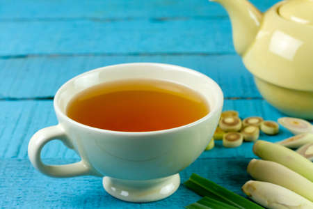 Cup of hot lemongrass tea with sliced and green leaf on blue wooden background. Lemongrass for healthy herbal drink concept.の写真素材