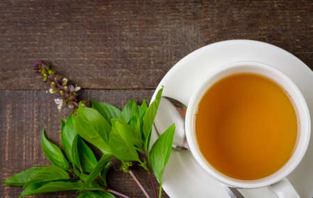 Basil tea in white cup ceramic with green leaf on rustic wooden table, top view. Basil is food and herb for healthy.の写真素材