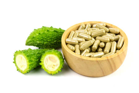 Bitter gourd or bitter melon capsules on wooden bowl and fresh bitter gourd isolated on white background. Scientific name is Momordica charantia.の写真素材
