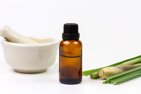 Lemongrass oil in bottle with fresh lemongrass and mortar and pestle isolated on white background.の写真素材