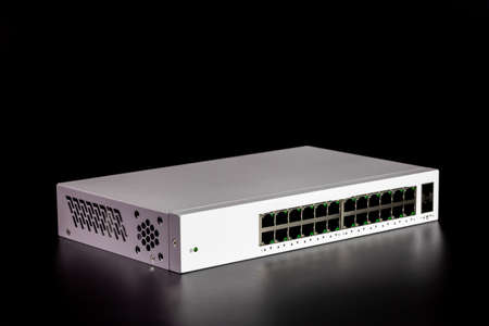 24-port gigabit switch white color isolated on black background. Components to create local area network for share data and device.の写真素材