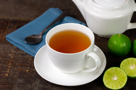 Hot tea in white cup with fresh lime on rustic wooden background.の写真素材