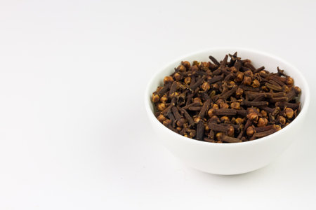 Cloves in white bowl isolated on white background, copy space. Herbal cloves have a fragrant and spicy flavor.の写真素材
