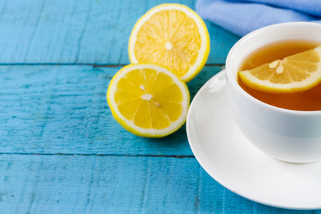 Cup of hot tea and lemon on blue wooden table.の写真素材
