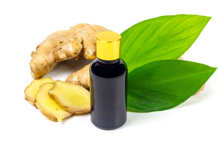 Ginger essential oil in bottle and fresh ginger with green leaf isolated on white background. The scientific name is zingiber officinale. Herbs for health care concept.の写真素材