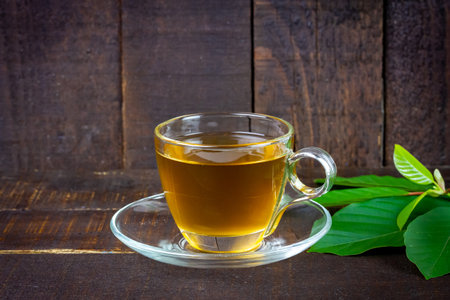Mitragyna Speciosa Korth or kratom tea in transparent cup wtih green leaf on rustic wooden background.の写真素材