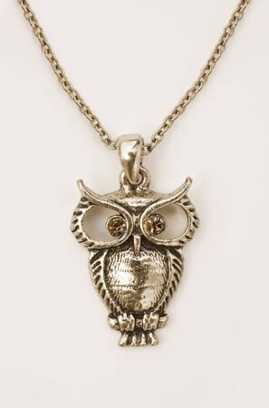 Close up of a gold owl pendant on whiteの写真素材