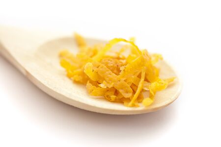 Fresh lemon zest on a wooden spoon, on white backgroundの写真素材