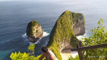 A Man stand on cliff, looking back blue oecean.  enjoy the summer holiday.  Summer holiday on kelingking beach,Nusa Penida Bali, Indonesia.の写真素材