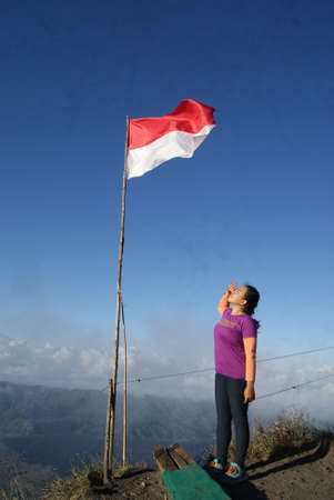 Indonesian woman with Indonesian flag on the top of a mountainの写真素材