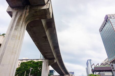 Bangkok, Thailand - OCTOBER 26, 2016: Public air train and finance buildings in urban of Bangkok, Thailand.  It photography in blue sky on background and little green trees on foreground.のeditorial素材