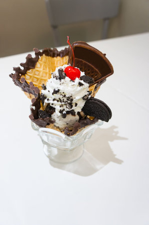 sundae ice cream with whip cream, wafer, in cup on white table.