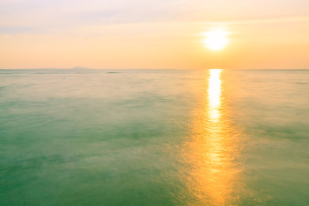 Colorful sunset and sea background with blue, purple and orange tones in abstract idea. It is small orange sun in sky at twilight time and copy space.の写真素材