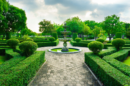 Sleepiness fountain in middle of crushed rock road are luxury garden in Bangkok, Thailand. This line of crushed rock road go straight to fountain concept,  forest and blue sky in a background.の写真素材