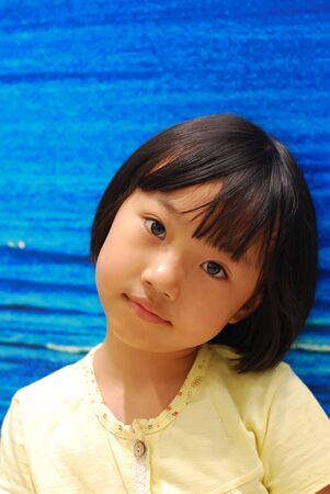 Asian little girl on blue backgroundの写真素材