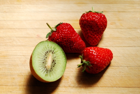 Strawberry and kiwi on a chopping boardの写真素材
