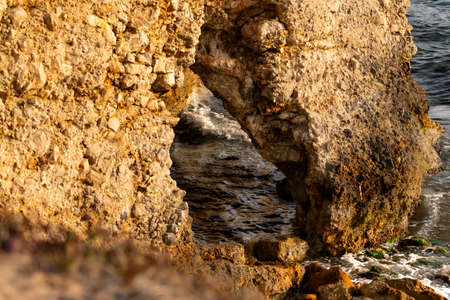 sea framed by a rock arch at sunset in eastern Sicily, in Sampieriの写真素材