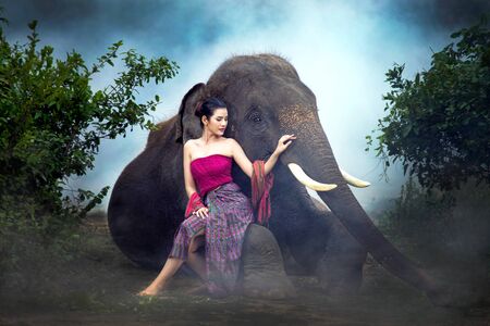 The asian girl took a cane to feed the elephants.の写真素材