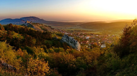 Panoramic picture of a beautiful autumn landscape, castle ruin above little village in PÃ¡lava protected landscape area in Czech republic at sunriseの写真素材