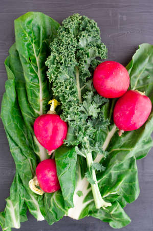 Leafy greens and radishes over gray backgroundの写真素材