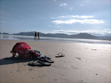 a bag and a pair of slippers on the beach in the morningのeditorial素材