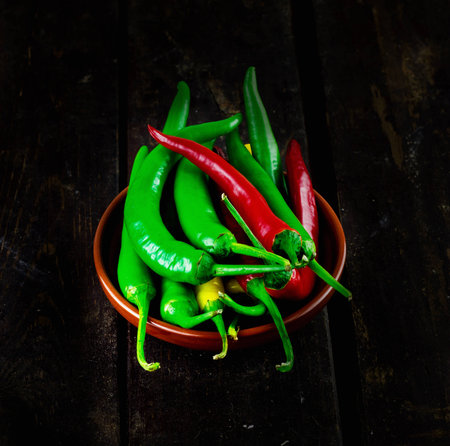 Red And Green Hot Chili Peppers in bowl over wooden backgroundの写真素材