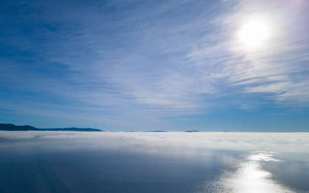 Morning fog over the sea with sun shining and reflecting in the seaの写真素材