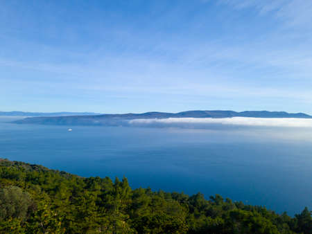 Morning fog over the sea with sun shining and reflecting in the seaの写真素材