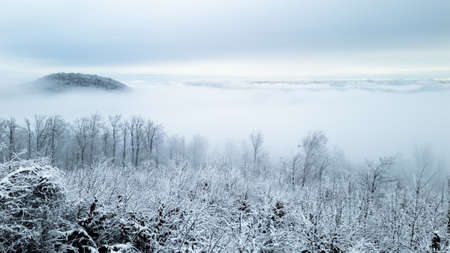 A mountain view of the landscape above the clouds on a snowy winter dayの写真素材