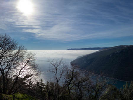 Morning fog over the sea with sun shining and reflecting in the seaの写真素材