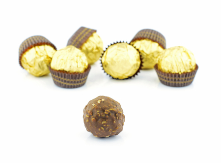 chocolate balls with almond in a gold foil paper on white backgroundの写真素材