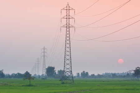 Electricity transmission pylon  in the field on sunsetの写真素材