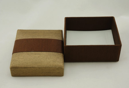 Opened gift box packaging, the exterior is made from fabric with gold and brown color.
