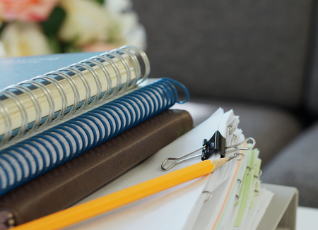 Three notebooks, yellow pencil and stack of document placed on desk at office.の写真素材