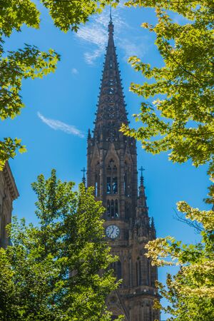 Cathedral over blue sky and framed by tree branchesの写真素材