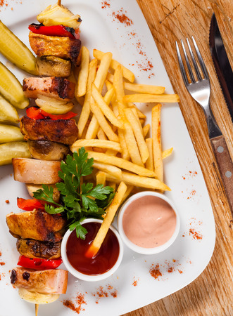 Chips and skewers on a white plateの写真素材